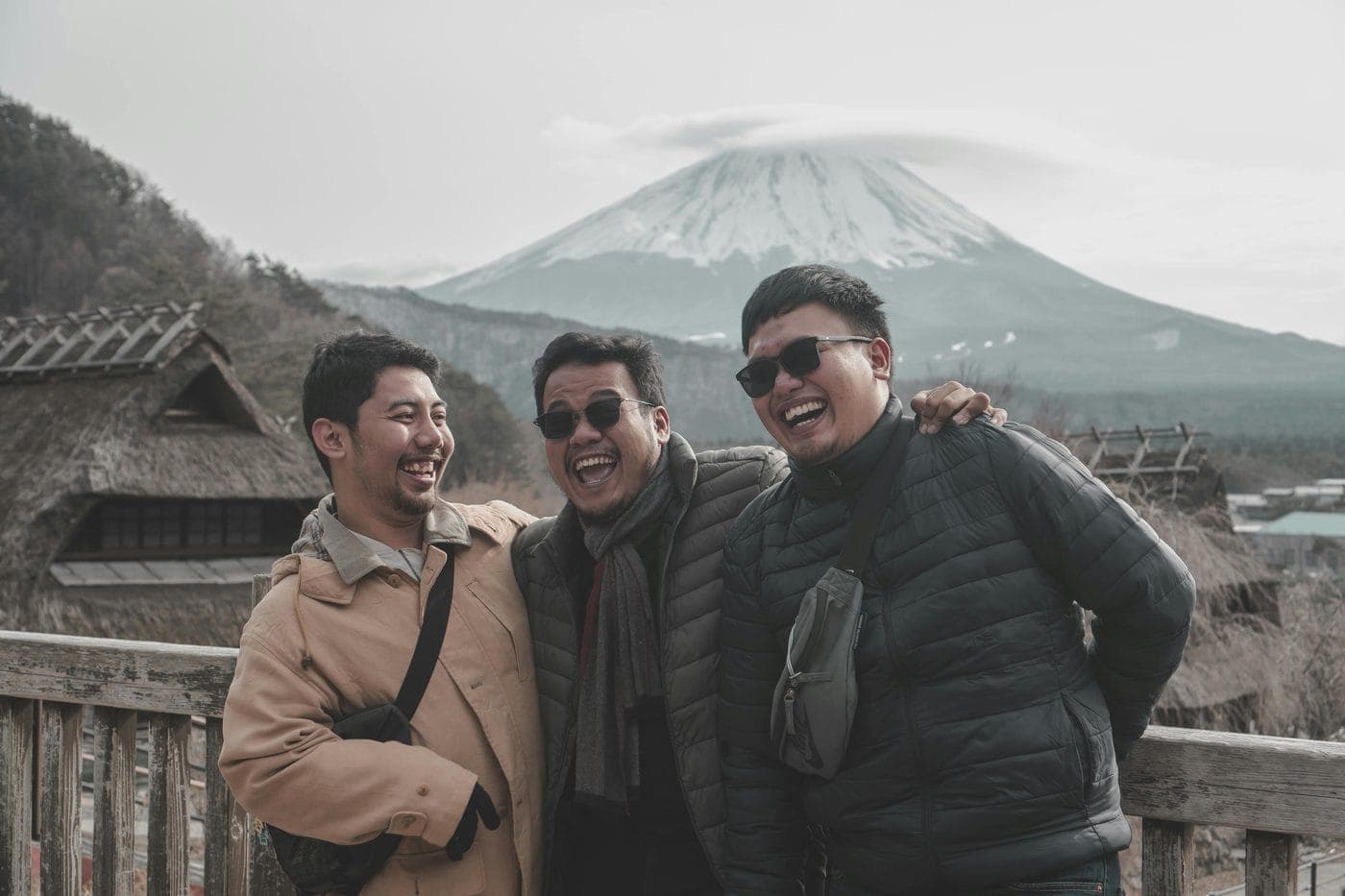 Three friends laughing on a trip in front of a mountain