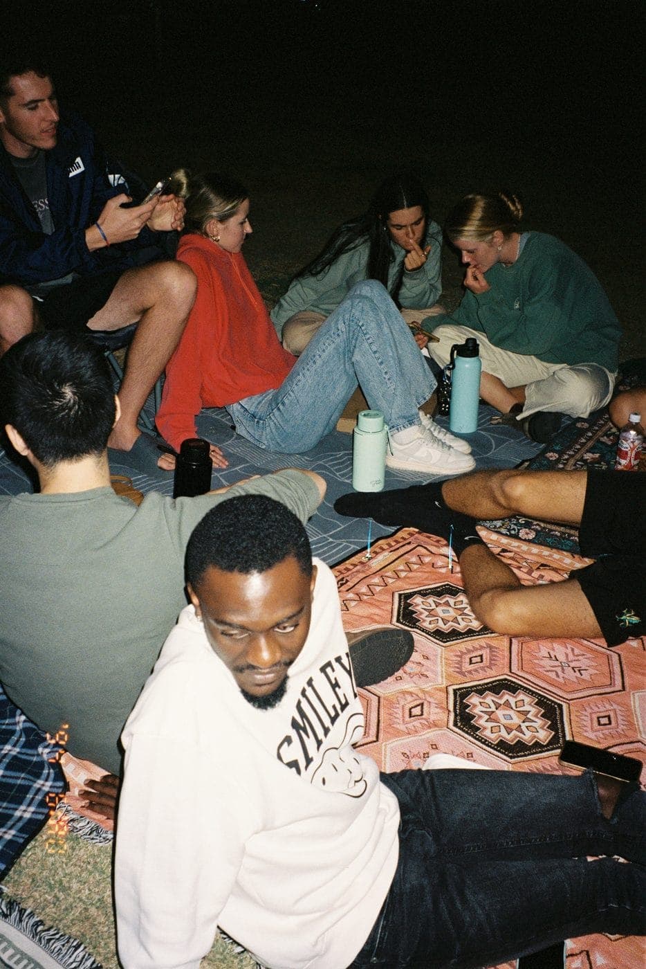 A mixed friend group hanging out together at night on a trip