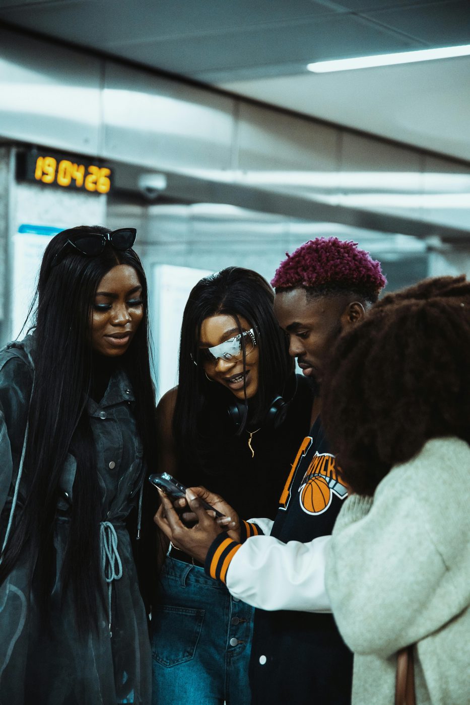 A group of friends huddled over a phone deciding plans together