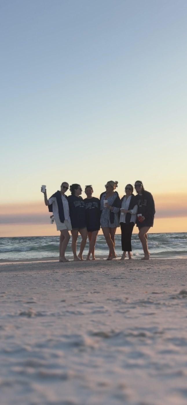 A group of friends together on the beach at sunset